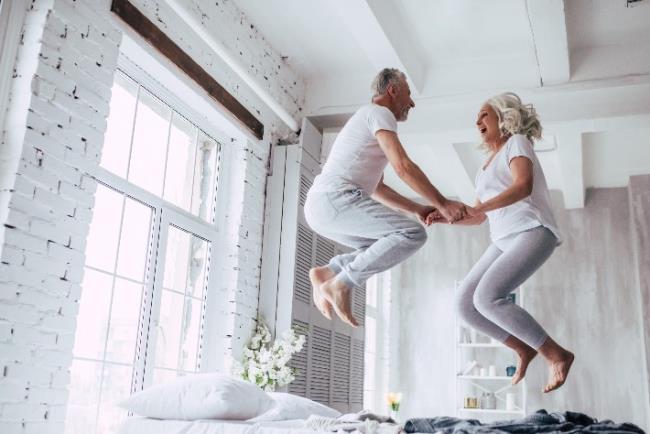 זוג מבוגרים קופץ בהנאה על מיטה, מראה כי גיל הוא רק מספר